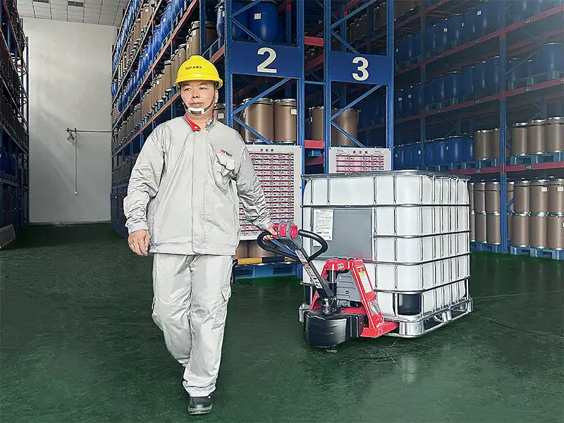 Image: Worker pulls a pallet truck with an IBC container in the warehouse